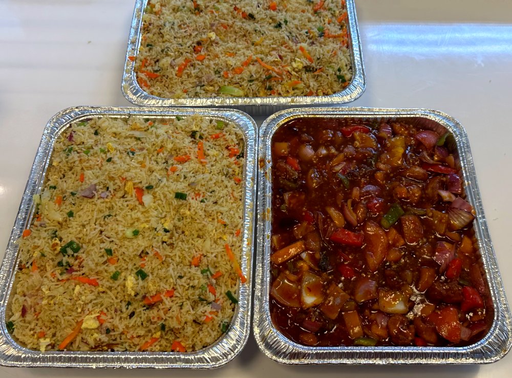Catering trays of vegetable fried rice and devilled chicken
